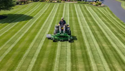 Commercial mower creating precise mowing stripes on lush lawn in Harrisburg, PA landscaping service